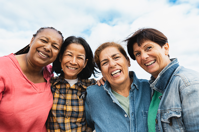 Happy multiracial senior women having fun smiling into the camera at house rooftop Happy multiracial senior women having fun smiling into the camera at house rooftop