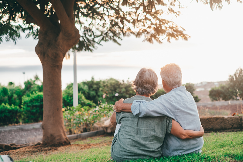 Happy grey haired middle aged couple Happy grey haired middle aged woman snuggling to smiling older husband, enjoying tender moment at park. Bonding loving old family couple embracing, looking sunset